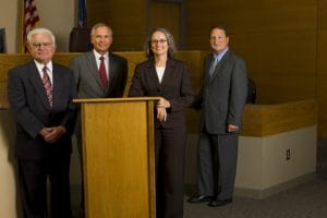 Photo of Jack Marcil, Ron McLean, Jane Dynes and Joseph Wetch standing behind a podium in a coutroom